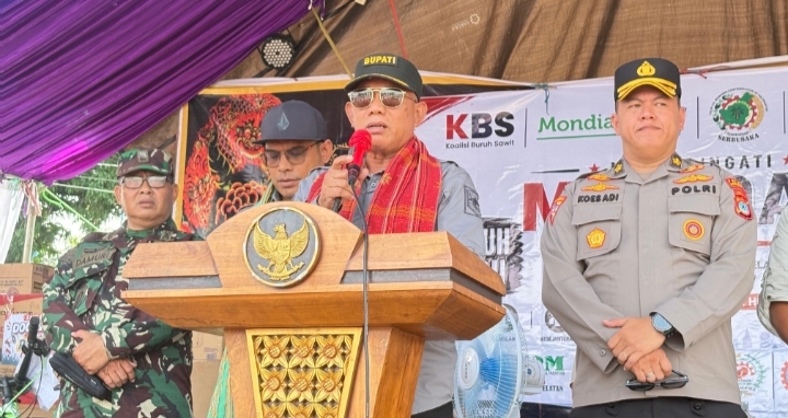Bupati Kotabaru Muhammad Rusli berpidato di podium pada peringatan May Day 2026 di Kelumpang Hulu, didampingi unsur TNI dan Polri