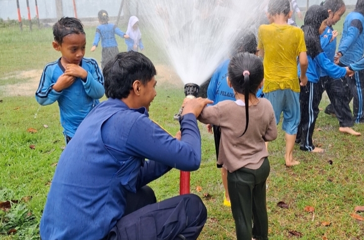 Petugas Damkar Tanah Laut mendampingi siswa TK Ar Raudah mencoba selang pemadam air saat edukasi mitigasi kebakaran di Pelaihari.