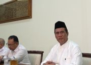 Menteri Pertanian dan Kepala Badan Pangan Nasional, Amran Sulaiman, mengenakan baju putih dan peci hitam saat menghadiri pertemuan resmi membahas sektor pertanian dan ketahanan pangan nasional.
