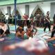 Beberapa pria bercelana panjang dan pendek sedang potong daging di atas terpal di tanah