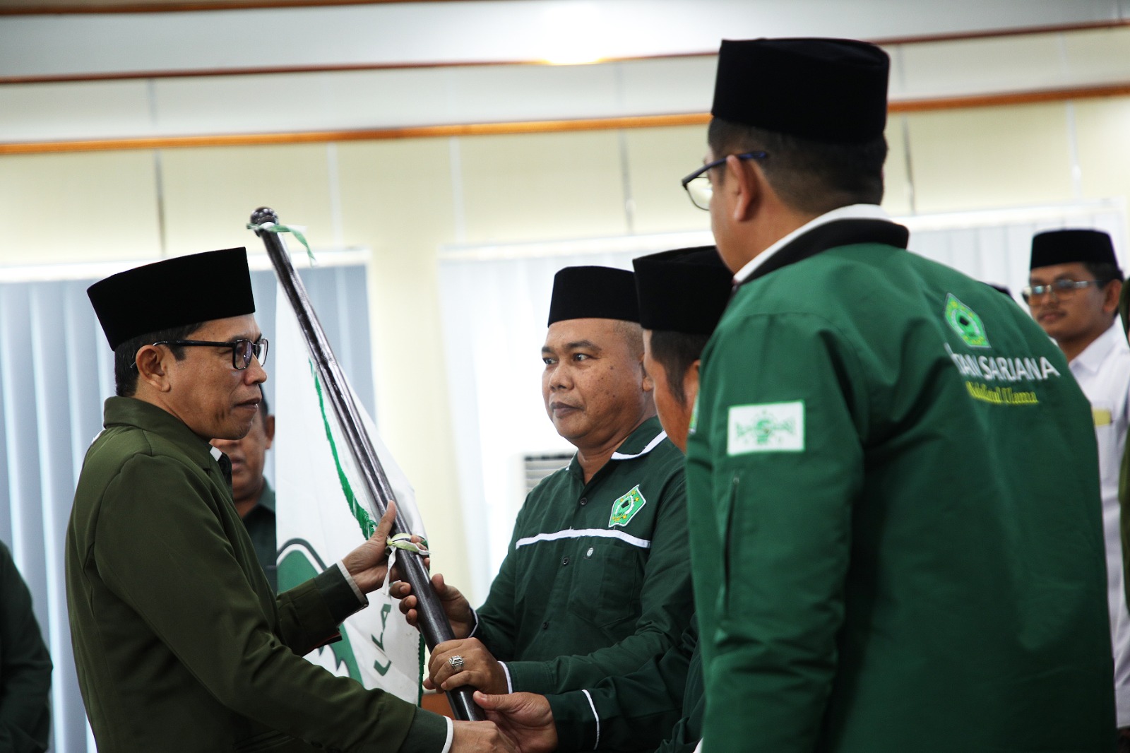 Pengurus menyerahkan bendera Pataka ISNU kepada Ketua PC ISNU yang baru dilantik.