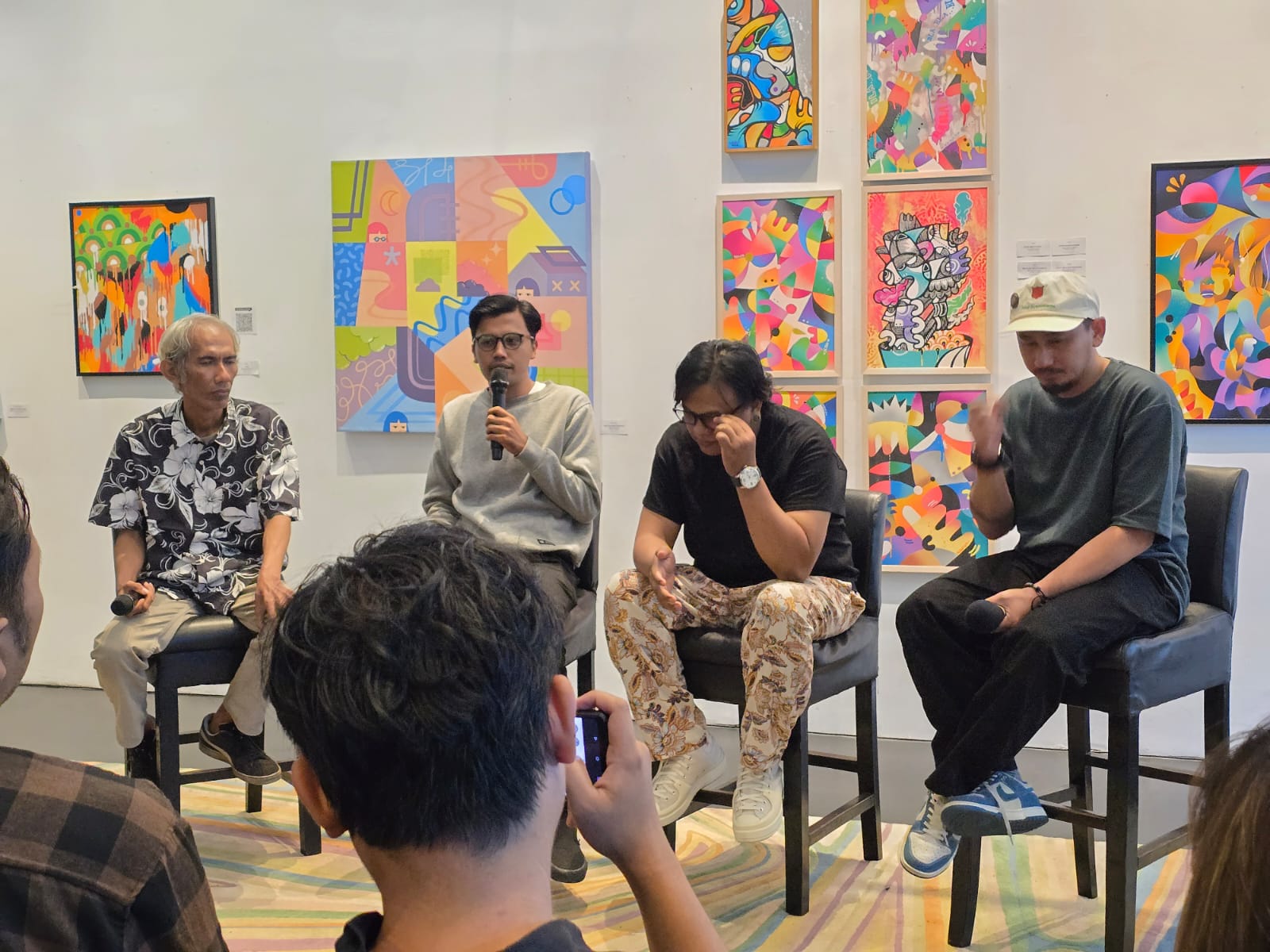 Anas Hope berdiri di samping lukisannya, menjelaskan proses kreatif.