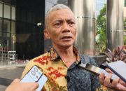 Pria berpakaian batik bicara di depan wartawan