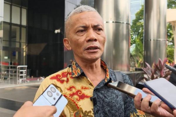 Pria berpakaian batik bicara di depan wartawan