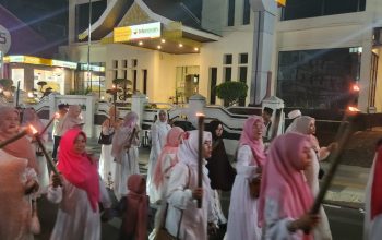 Kerumunan remaja membawa obor menyala berjalan di malam hari