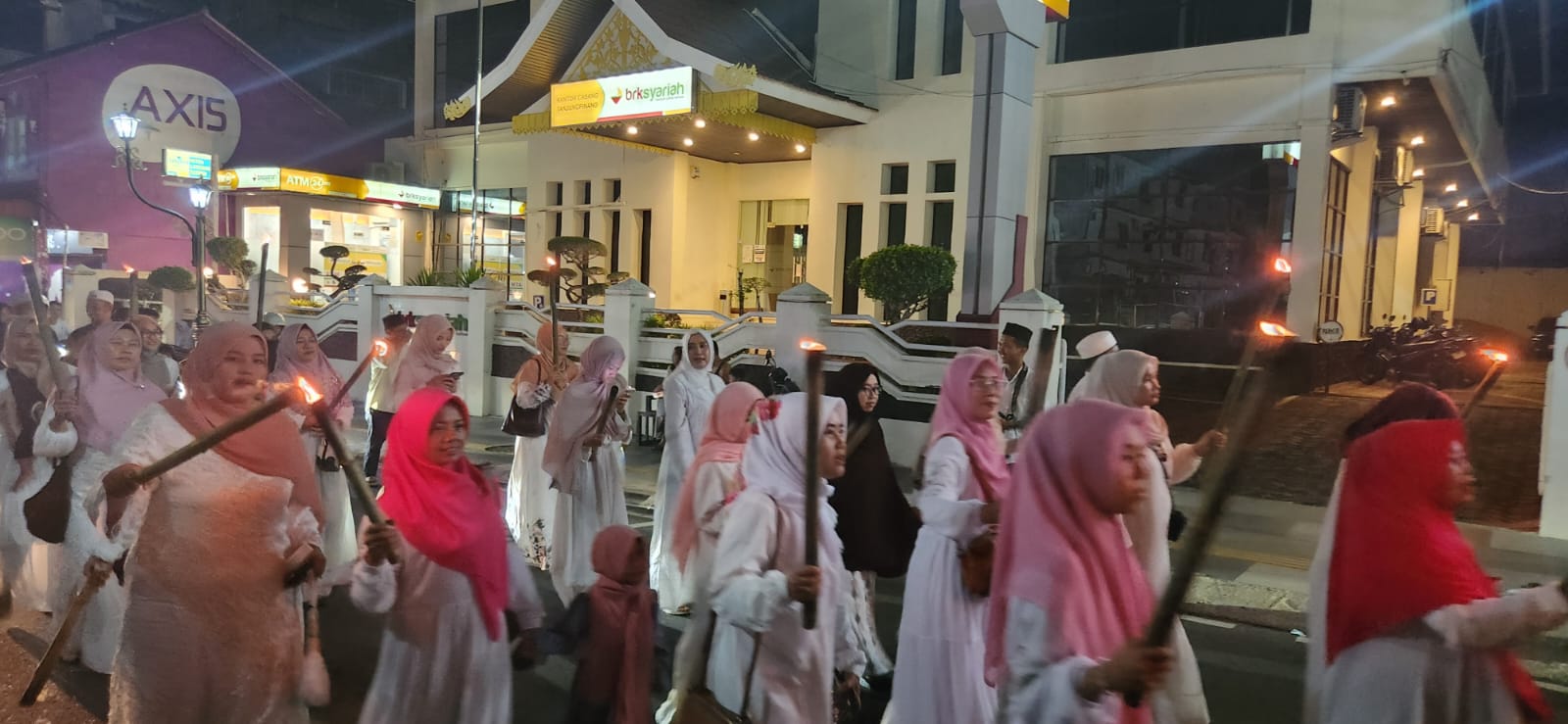 Kerumunan remaja membawa obor menyala berjalan di malam hari
