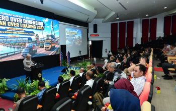 Tiga orang duduk di meja panelis, latar spanduk seminar