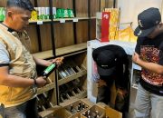Polisi memeriksa tumpukan botol miras di dalam kardus