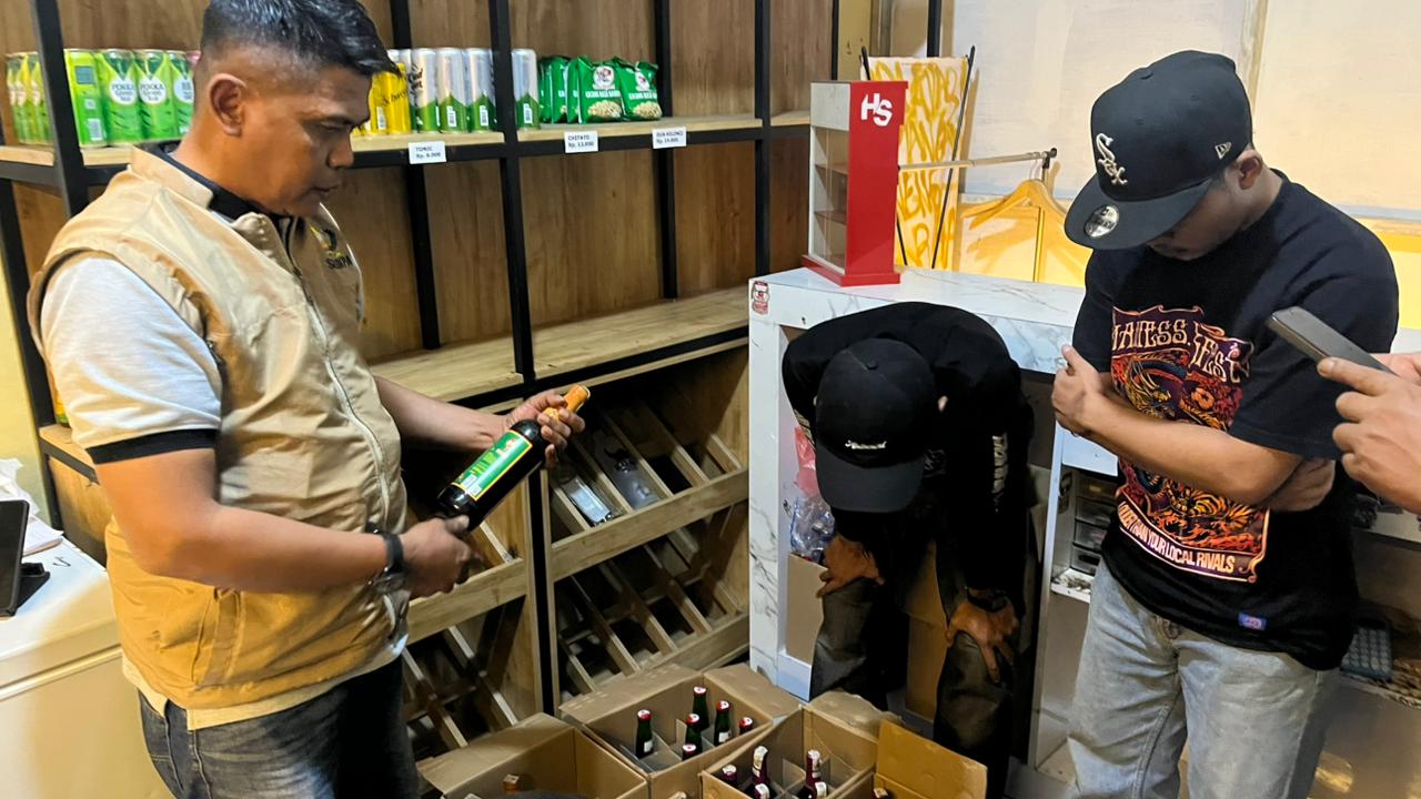 Polisi memeriksa tumpukan botol miras di dalam kardus