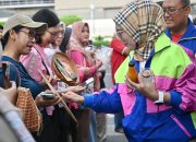 Perempuan berdiri di atas panggung, latar spanduk PFpreneur