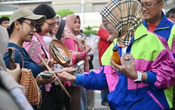 Perempuan berdiri di atas panggung, latar spanduk PFpreneur