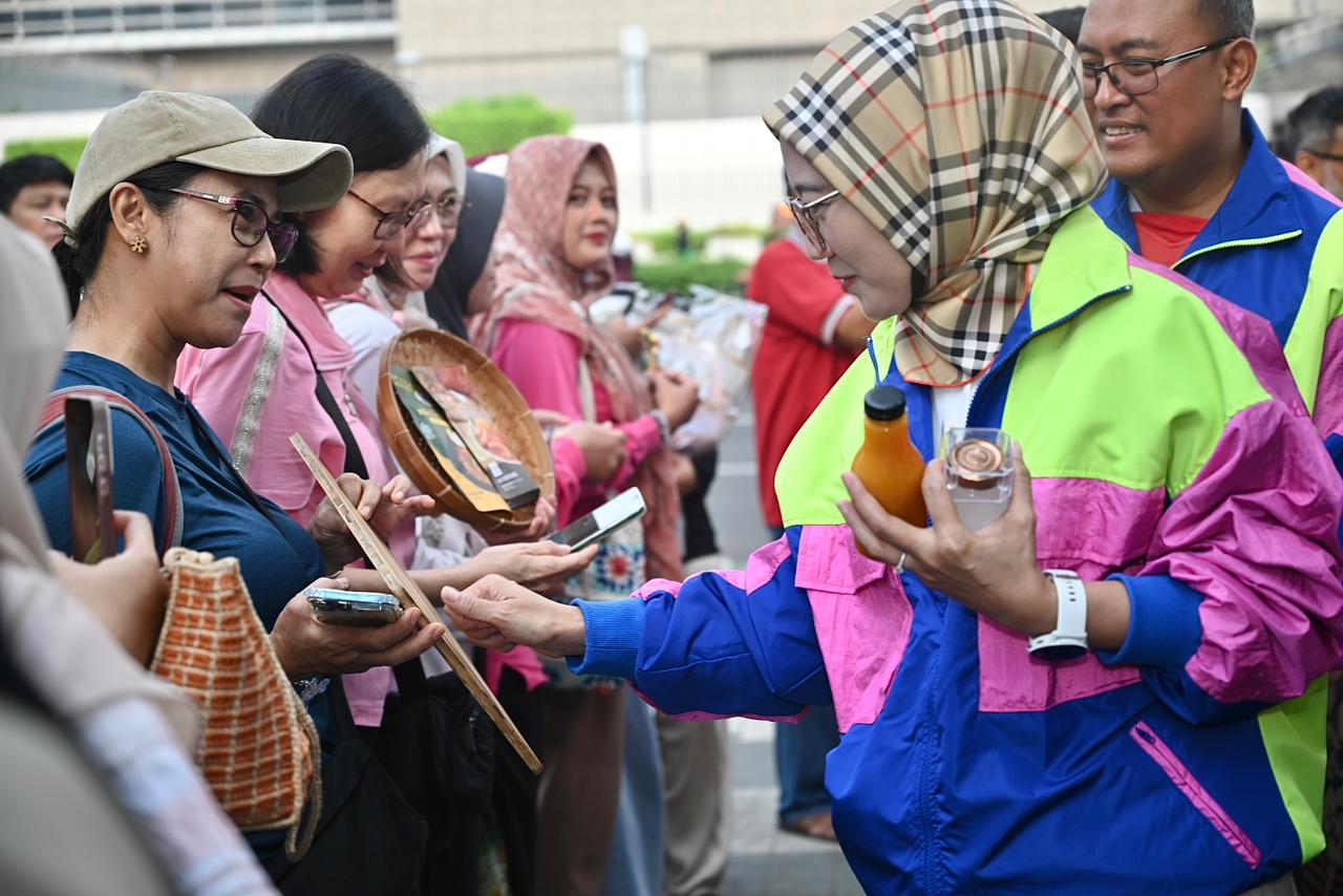 Perempuan berdiri di atas panggung, latar spanduk PFpreneur