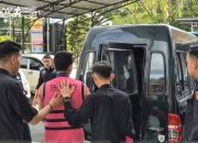 Pria berseragam tahanan digiring polisi ke mobil di halaman kantor
