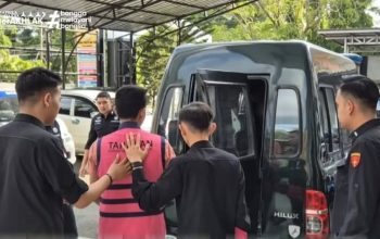 Pria berseragam tahanan digiring polisi ke mobil di halaman kantor