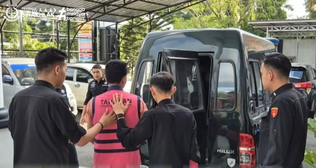 Pria berseragam tahanan digiring polisi ke mobil di halaman kantor