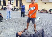 Tersangka berbaju tahanan menunjuk ke suatu titik di lokasi