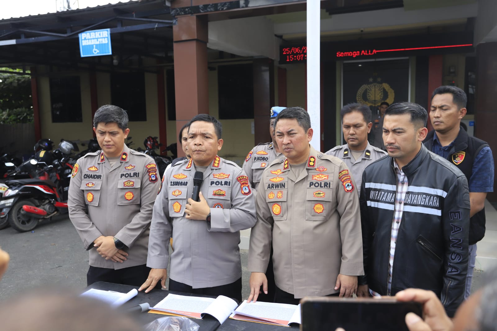 Polisi berbicara di depan mikrofon, latar spanduk Polresta Banjarmasin