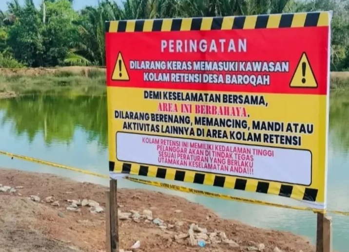 Plang peringatan di kolam retensi Desa Barokah