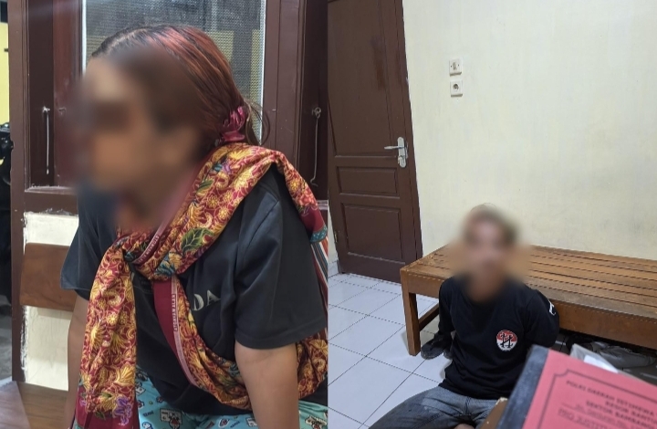 Dua tersangka duduk di ruang polisi, satu laki-laki satu perempuan