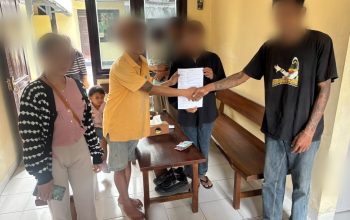 Dua pria bersalaman di ruang polisi, petugas dan wanita di samping mereka
