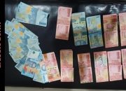Polisi menunjukkan uang dan kain kuning di atas meja