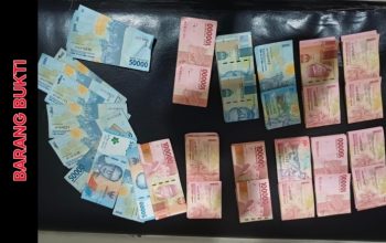 Polisi menunjukkan uang dan kain kuning di atas meja