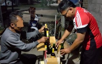 Botol-botol miras di atas meja, polisi berdiri di sampingnya