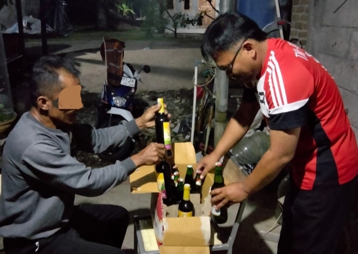 Botol-botol miras di atas meja, polisi berdiri di sampingnya