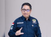 Pria berseragam dinas berbicara di depan papan informasi