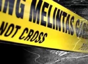 Garis polisi kuning melingkari area persawahan, latar belakang pohon dan langit sore