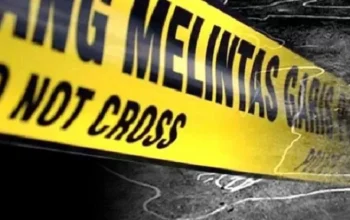 Garis polisi kuning melingkari area persawahan, latar belakang pohon dan langit sore