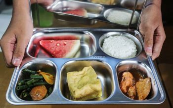 Hidangan nasi, lauk, sayur, dan buah dalam kotak makanan