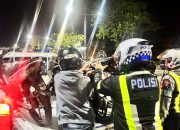 Personel Satlantas Polresta Banjarmasin menaikkan sepeda motor hasil penindakan patroli balap liar ke mobil patroli.