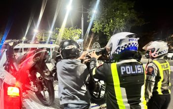 Personel Satlantas Polresta Banjarmasin menaikkan sepeda motor hasil penindakan patroli balap liar ke mobil patroli.
