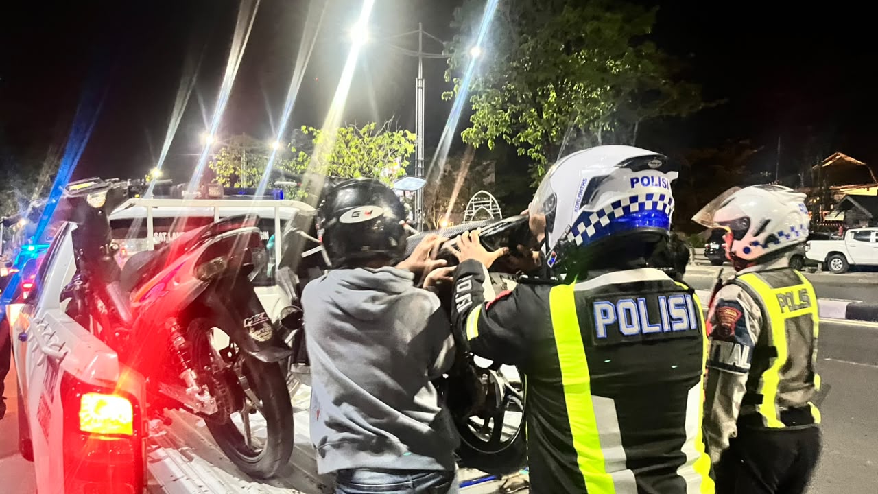 Personel Satlantas Polresta Banjarmasin menaikkan sepeda motor hasil penindakan patroli balap liar ke mobil patroli.